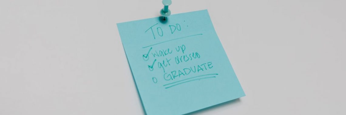 A blue sticky note with a graduation to-do list pinned to a white surface.